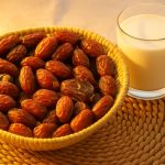 خرمای خاصویی بدون شیره در ظرف حصیری بوشهری کنار لیوان شیر با نور ملایم صبح